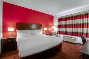 a large bed in a room with a red wall at Inn at Hunters Run in Watford City +37 photos
