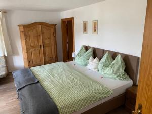 a bedroom with a bed with green and white pillows at Pension Oberwirt in Fischbachau