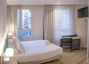 a bedroom with a white bed and a desk and a window at Hotel Mediterraneo Valencia in Valencia