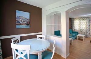 
a living room with a table, chairs and a painting on the wall at Apartamentos turísticos Jardines del Plaza in Peniscola
