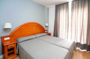 a bedroom with a bed with a wooden headboard and a window at Apartamentos turísticos Jardines del Plaza in Peniscola