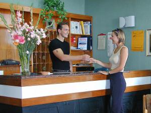 un hombre y una mujer estrechando la mano en un mostrador en Hotel Nettuno, en Soverato Marina