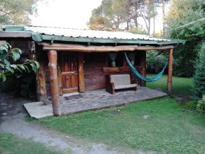 Cabaña de madera con hamaca en un patio en Cabañas Monje en Tandil