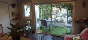 a living room with a glass table and a patio at Secret Garden - Chez Gilles et Tra - Maison d hôte -T2 super mignon, neuf et indépendant , dans cadre agréable et zen in Valergues
