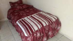 a bed with a red and white blanket on it at Casa Neblina confort y tranquilidad. in León
