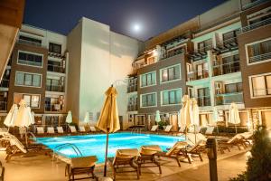 a pool with chairs and umbrellas next to a building at Menada Horyzont Apartments in Sozopol