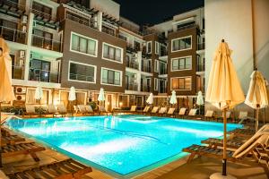 a swimming pool in a hotel with chairs and umbrellas at Menada Horyzont Apartments in Sozopol