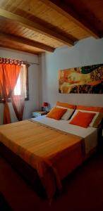 a bedroom with a large bed with orange sheets and a window at Apartment Trezza in Acitrezza