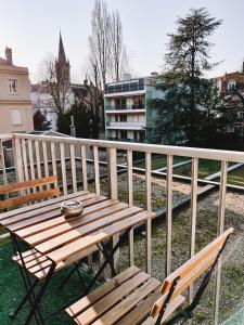 uma mesa de madeira e 2 cadeiras numa varanda em Studio bohème - Centre - Proche gare em Mulhouse