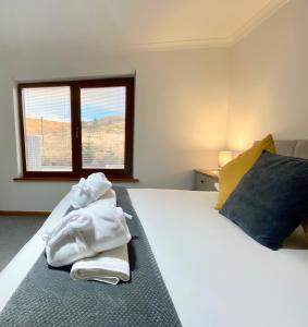 ein Schlafzimmer mit Handtüchern auf einem Bett mit Fenster in der Unterkunft Highland Stays - Ben View Room & Jacuzzi Bath in Fort William