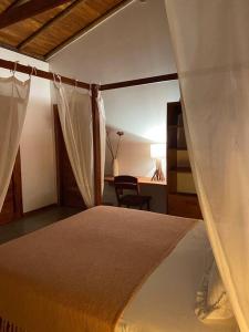 a bedroom with a canopy bed and a desk at La belle de jour in Fortim