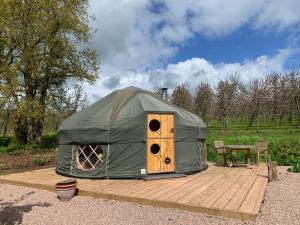 a green tent sitting on a wooden deck with a table at Dragon Orchard Retreat in Ledbury