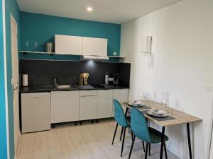 a kitchen with a table and two blue chairs at VITTEL LOC'S - LE 147 - Un Havre de PAIX - CALME in Vittel