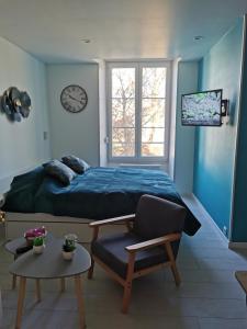 a bedroom with a bed and a chair and a clock at VITTEL LOC'S - LE 147 - Un Havre de PAIX - CALME in Vittel