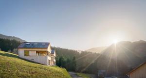 una casa en una colina con el sol en el fondo en Ferienhaus Bergfrieden Laterns auf 1.170 m, en Laterns