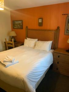 1 dormitorio con 1 cama blanca grande y mesita de noche en The Barrington Arms Hotel, en Shrivenham