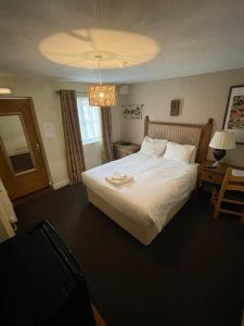 Habitación de hotel con cama y lámpara de araña. en The Barrington Arms Hotel, en Shrivenham