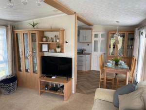a living room with a television and a kitchen with a table at Starlight Retreat in Swarland