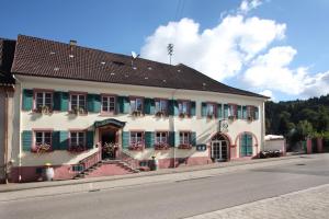 duży biały budynek z zielonymi okiennicami i schodami w obiekcie Landgasthof Rebstock w mieście Sulzburg