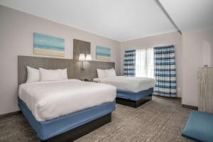 翡翠岛Lighthouse Suites - Best Western Signature Collection的有两张床和一把椅子的酒店房间