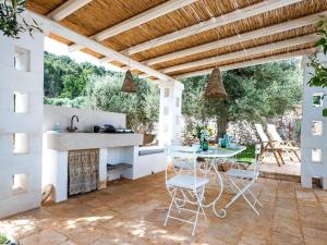 eine Außenküche mit einem Tisch und Stühlen auf einer Terrasse in der Unterkunft Trulli di Montepizzuto in Fasano