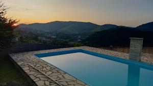 a blue swimming pool with a view of the mountains at Suite Requinte da Serra in Miguel Pereira