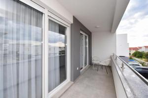 a balcony with large windows and a table and chairs at Apartman Bora 1 in Novalja