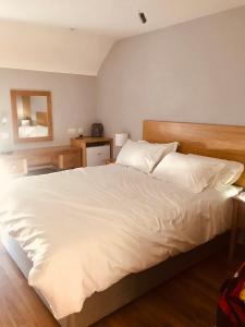 1 dormitorio con 1 cama grande con sábanas y almohadas blancas en Leanna's Lodge, Keshcarrigan en Leitrim