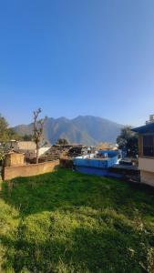 a green field with some buildings and mountains in the background at BlaBla House Rishikesh in Rishīkesh +150 photos