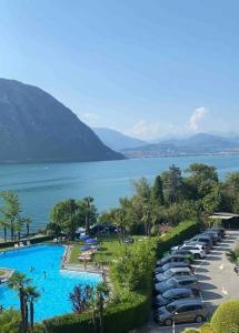 ein Parkplatz mit Autos neben einem großen Pool in der Unterkunft Holiday on The Lake Lugano 2 in Bissone