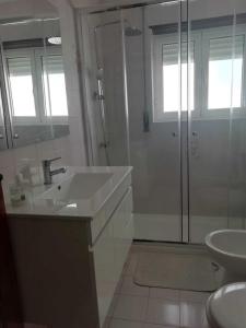 y baño blanco con lavabo y ducha. en Casas da Cacilda, en Nazaré