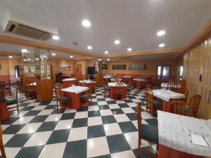 Un restaurante con mesas y sillas sobre un suelo a cuadros. en Hotel Nuevo Lorenzo, en Salamanca
