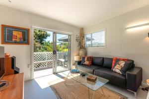 a living room with a black couch and a window at Four Palms Cottage - Onetangi Holiday Home in Onetangi