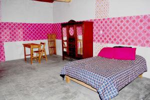 - une chambre avec un lit et une table avec un oreiller rose dans l'établissement Ojo de Luna Teotitlan, à Teotitlán del Valle