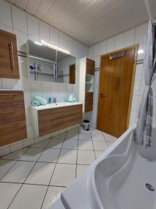 uma casa de banho com uma banheira, um lavatório e um espelho. em Ferienhaus Nannen em Rechtsupweg