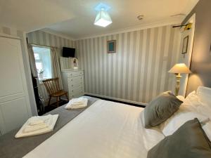 a bedroom with a large white bed and a chair at Bryn Noddfa in Morfa Nefyn