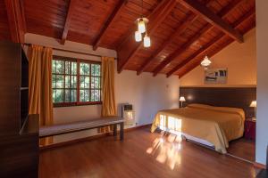 1 dormitorio con cama y ventana grande en Cabañas Villa Buriasco en Villa General Belgrano