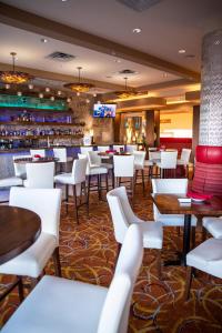 un restaurante con mesas y sillas blancas y un bar en Hotel 11, MOD A Sonesta Collection, en Calgary