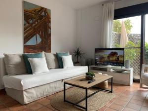 ein Wohnzimmer mit einem weißen Sofa und einem TV in der Unterkunft APARTMENT LA PEÑA ROJO WIFI in Tarifa