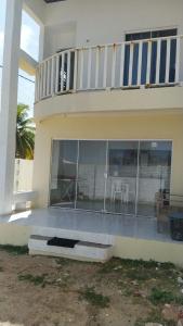 a house with glass windows and a balcony at DUPLEX BEIRA MAR TABATINGA in Nísia Floresta