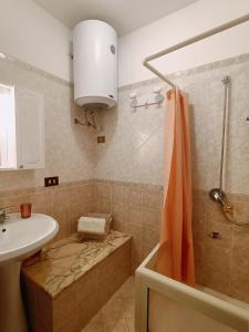 a bathroom with an orange shower curtain and a sink at La Sicilia in casa in Cinisi