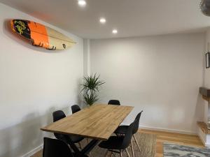 une salle à manger avec une table en bois et une planche de surf sur le mur dans l'établissement Casa da Sofia, à Leça da Palmeira
