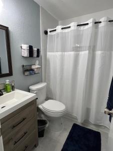 a bathroom with a toilet and a white shower curtain at CASA ATX- Private room and Bathroom in Quiet Neighborhood in Austin