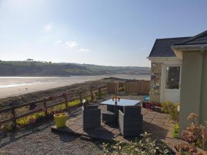a patio with a table and chairs next to the beach at Idyllic Inchydoney Beach Cottage - Amazing sea views, path to beach! in Cork
