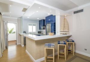 una cocina con armarios azules y una barra con taburetes en HB Comfortable Beachfront Holiday Apartment, en Estepona