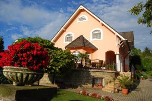 a house with a vase of red flowers in front of it at Barackvirág Vendégház in Tihany