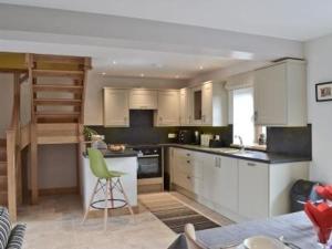 a kitchen with white cabinets and a green chair in it at BREATHTAKING VIEWS with a HOT TUB - Bwlch Cliced in Talybont