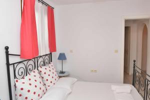a bedroom with a white bed with red and white pillows at Paradisia Villas in Naxos Chora