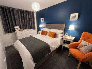 um quarto com uma cama e uma cadeira laranja em Delightful, central 3 bedroom house with garden. em Inverness