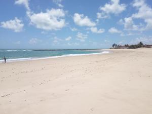 una persona caminando por una playa de arena cerca del océano en DUPLEX BEIRA MAR TABATINGA, en Nísia Floresta